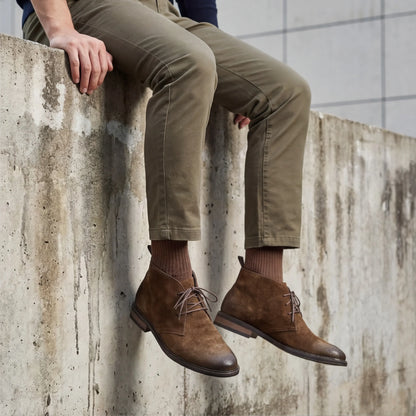 Bota Pampa Camurça com calça oliva, sentado num muro de concreto